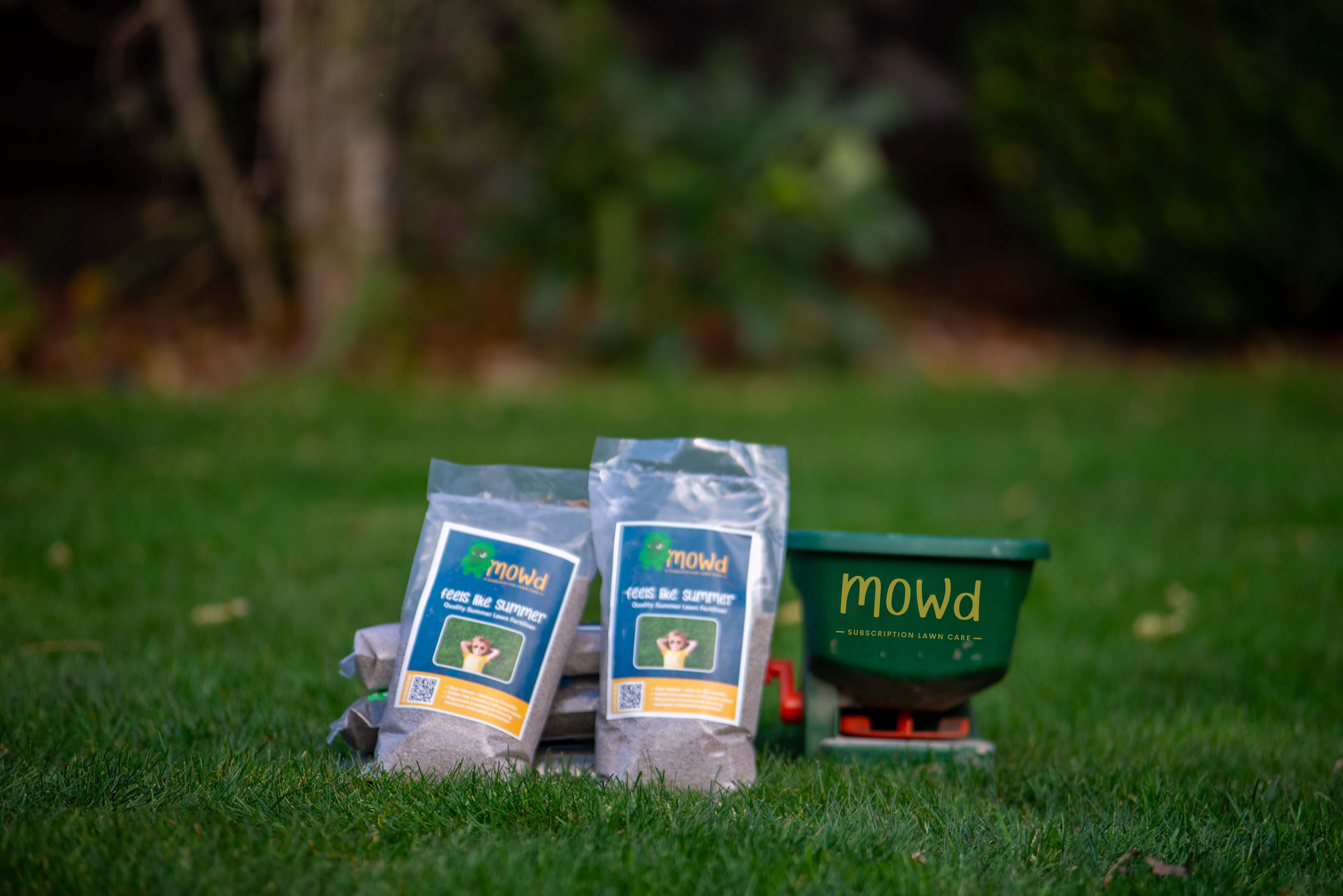 Mowd Feels like Summer - Summer Lawn Feed products on a garden lawn with a Hand Fertiliser Spreader